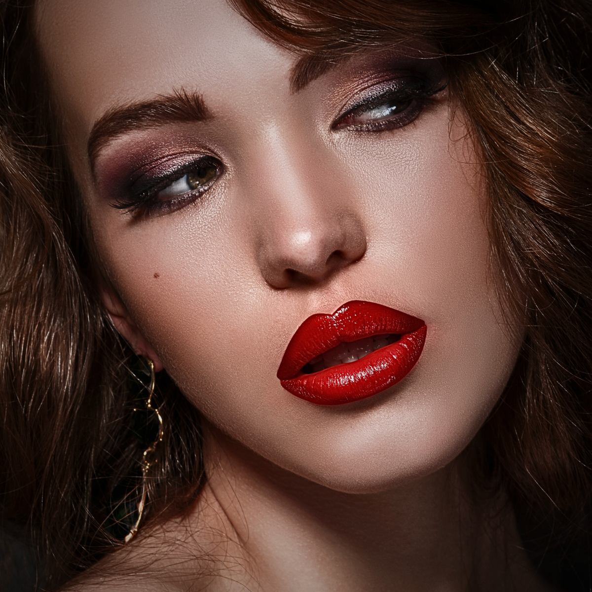 A beautiful brunette model wearing ruby red lipstick in a close-up photograph. © 2025 Kandillyns.com